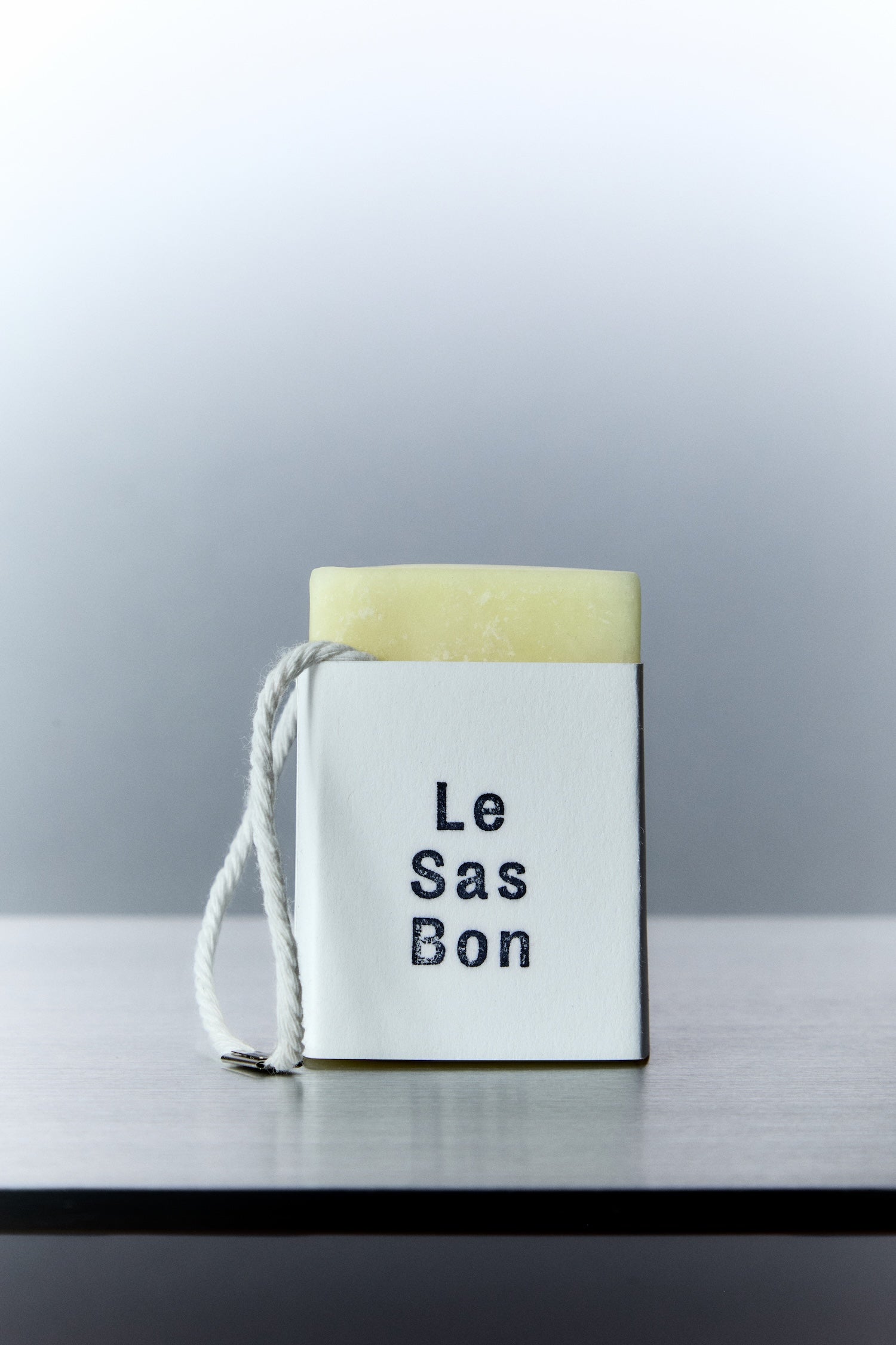 Cube of scented wax melt in Le Sas Bon branded sleeve with rope dangling outside