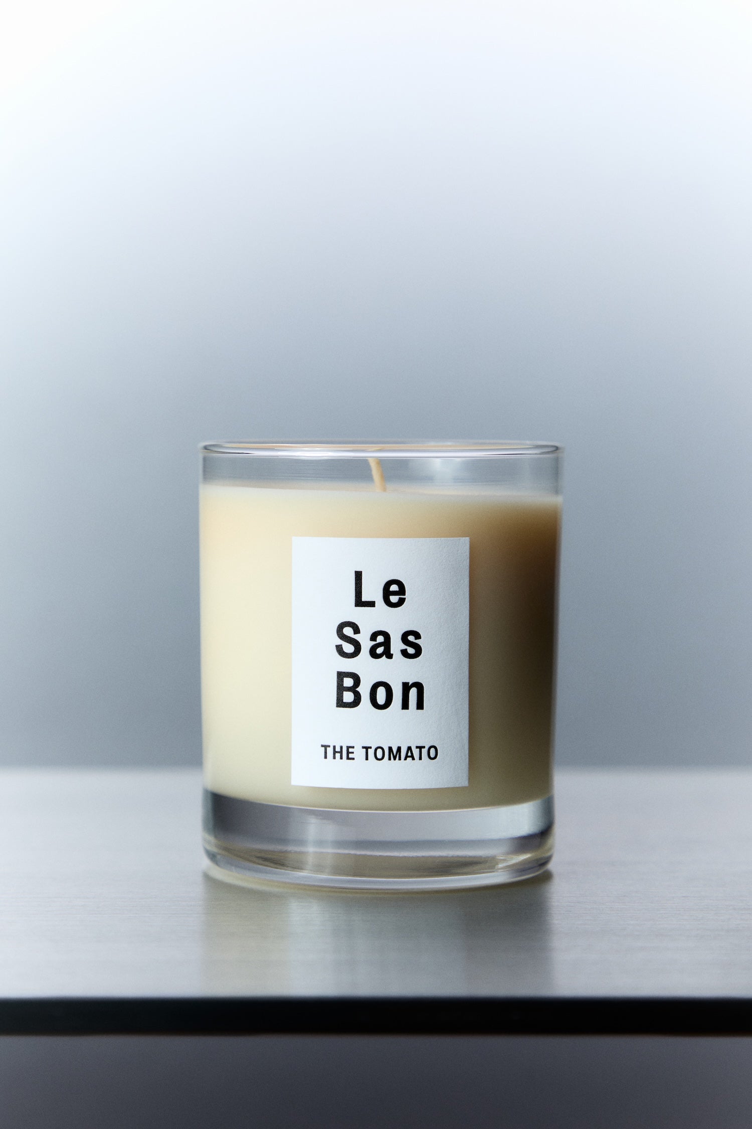 Le Sas Bon "The Tomato" natural and vegan candle in glass vessel with white rectangle branded sticker against a silver background