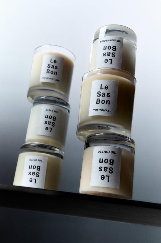 6 stacked Le Sas Bon candles in 2 columns showcasing a variety of candles each with a Le Sas Bon sticker label against a grey gradient backdrop