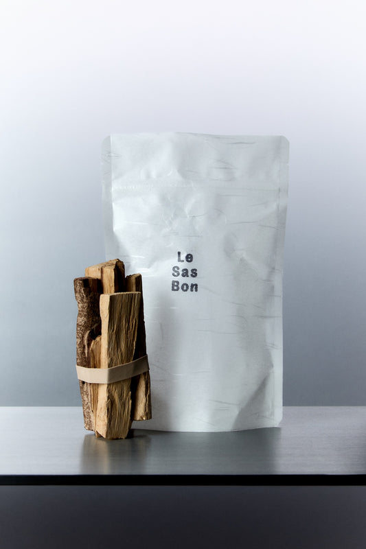 Standing bundle of palo santo raw cut sticks next to white rectangular Les Sas Bon branded packaging