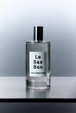 Cylinder glass spray bottle with Le Sas Bon "The Downtown" clear liquid room spray and branded label against grey gradient background 